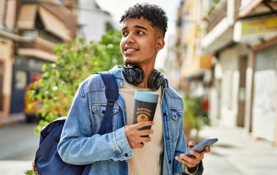 A young man holding a goodcup and a mobile phone with the goodbag app